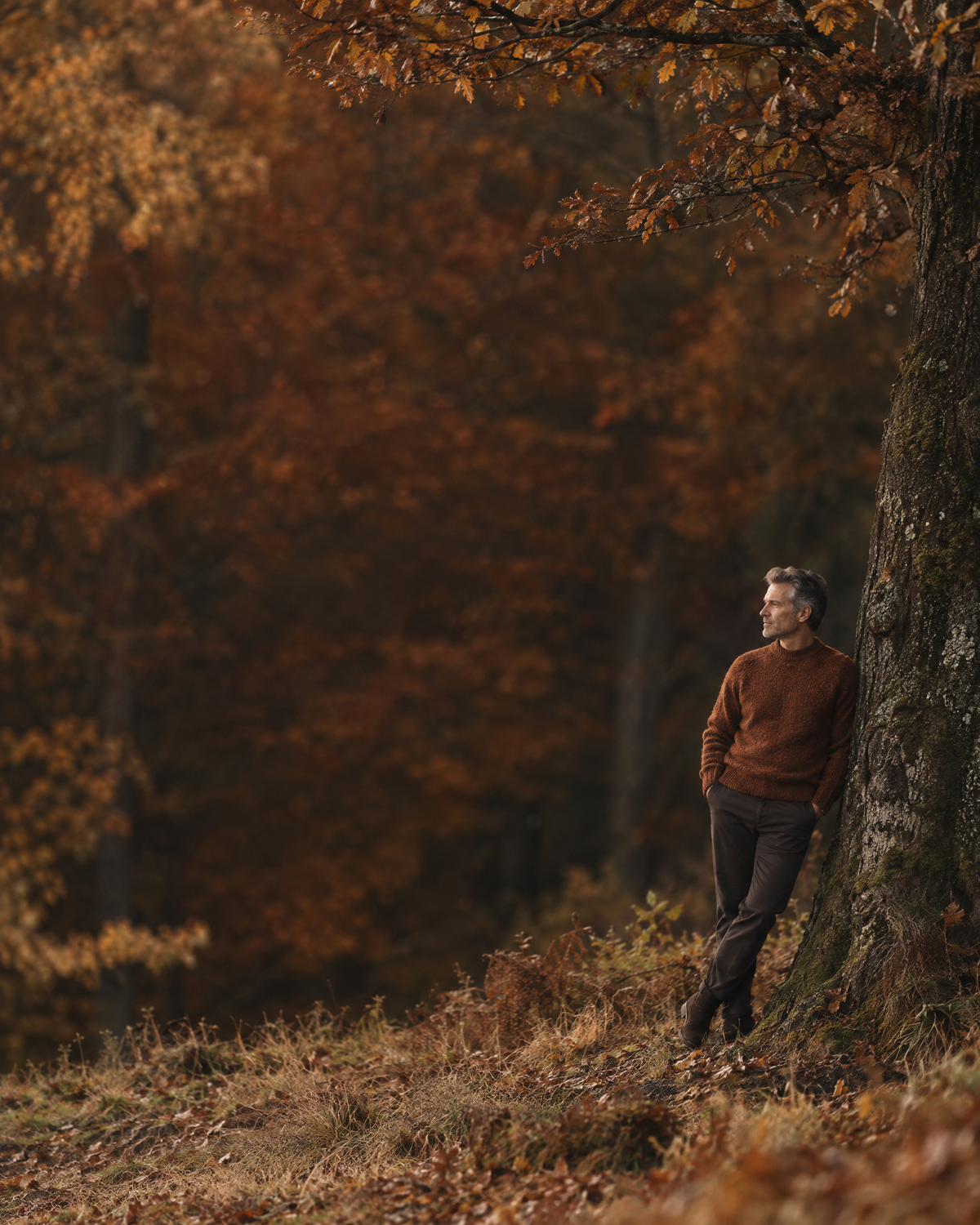 Mann im rostbraunen Wollpullover am herbstlichen Waldrand